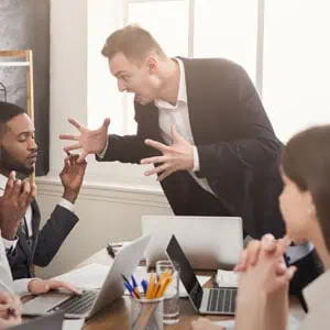 A tense meeting in a conference room as one man accuses another, creating a hostile work environment - Working For Workers